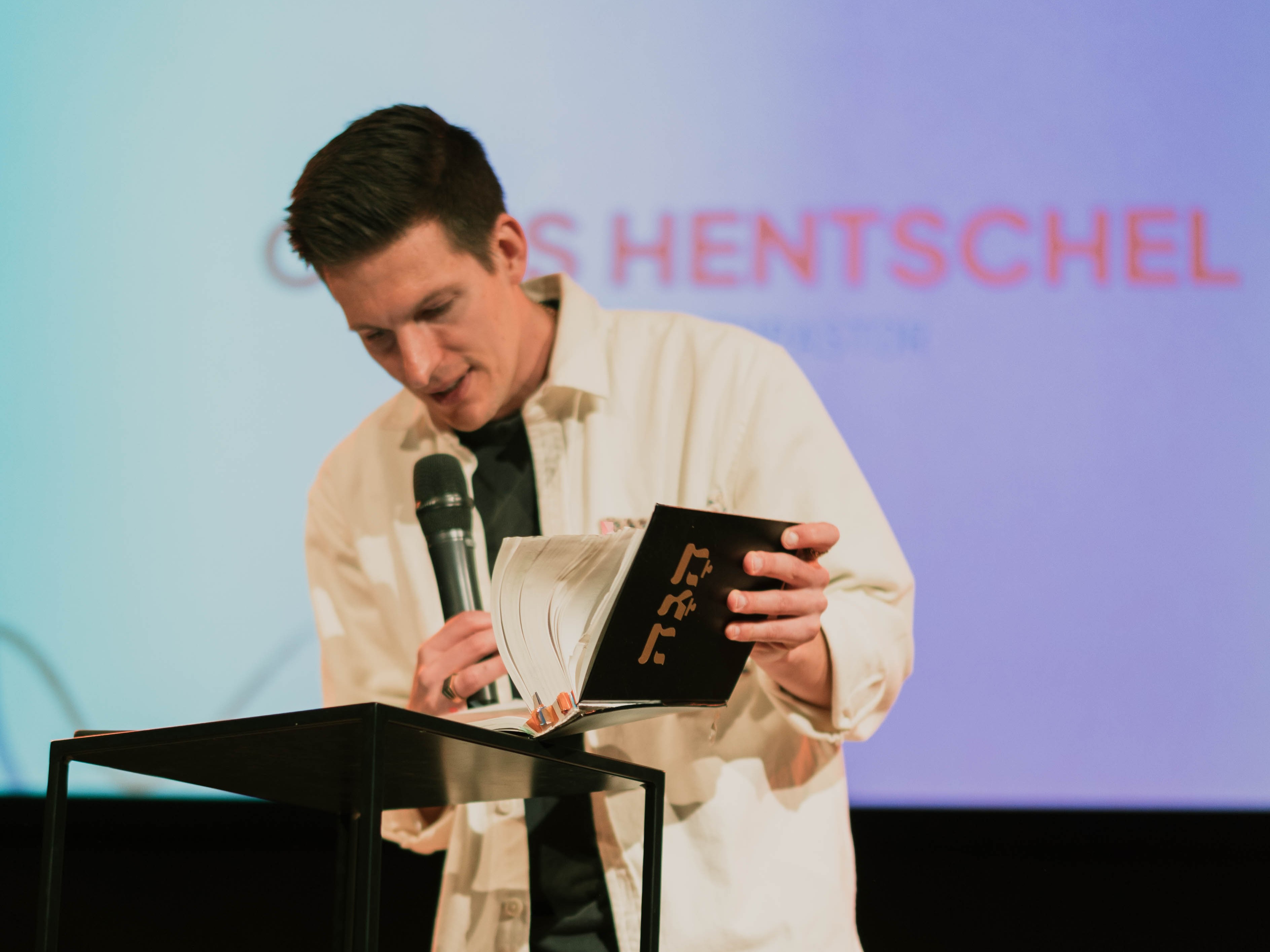 Chris Henschel auf der Bühne mit Bibel beim predigen